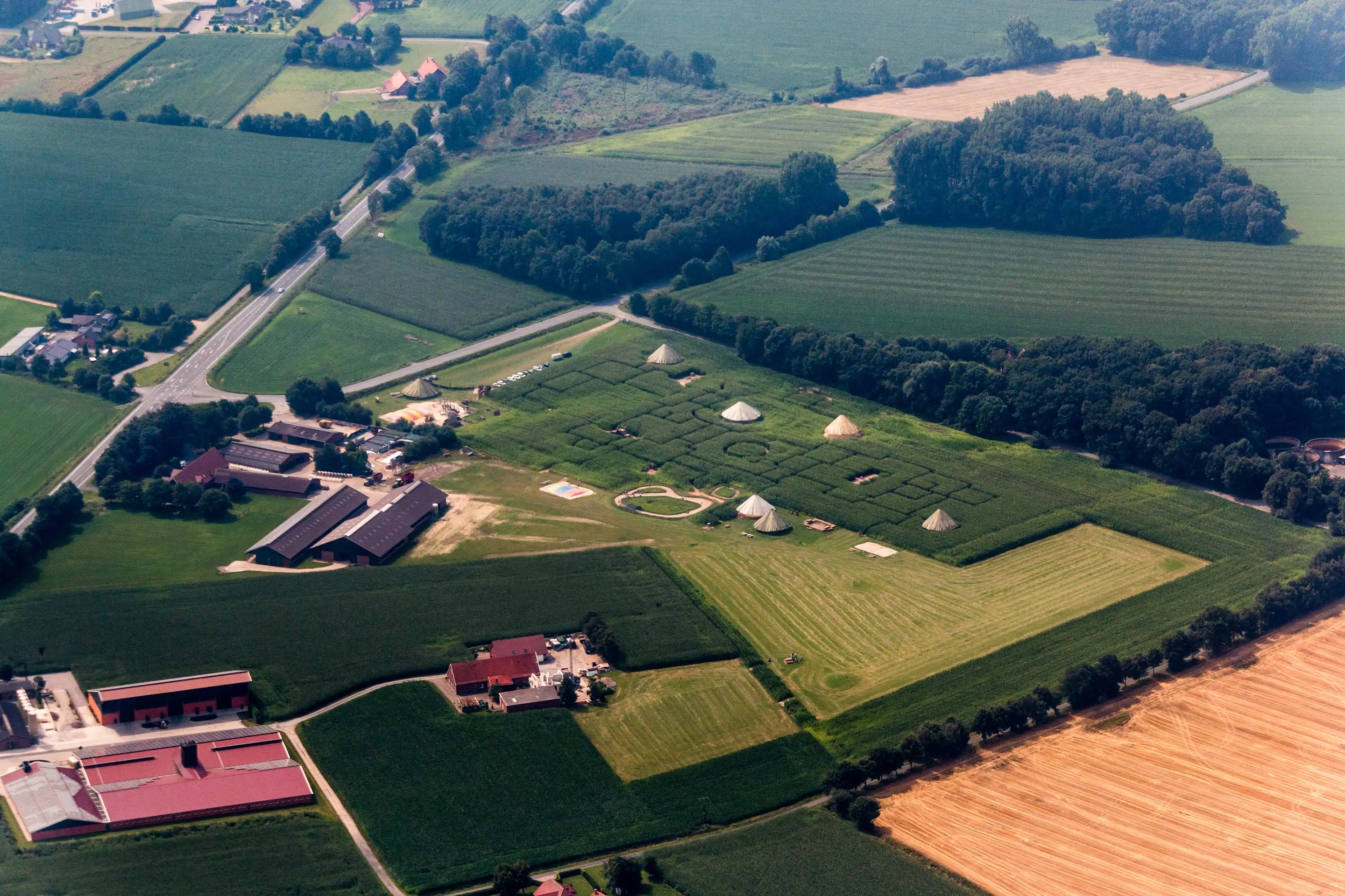 Maislabyrinth mit weißen Zelten zwischen Feldern und Höfen bei Südlohn, aus der Luft
